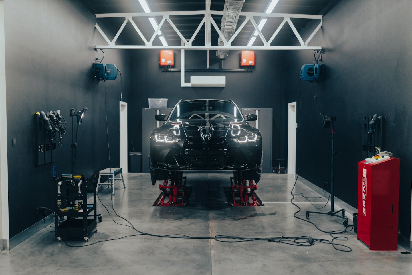 Luxusné čierne auto na hydraulických zdvihákoch v dielni.